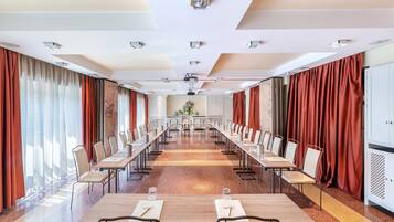Ein Konferenzraum mit einem langen Tisch, Stühlen und einer Projektionsleinwand.