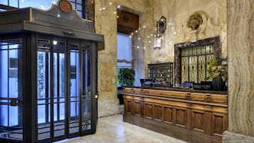 Un hall con paredes de mármol, un mostrador de recepción y un amplio ventanal.