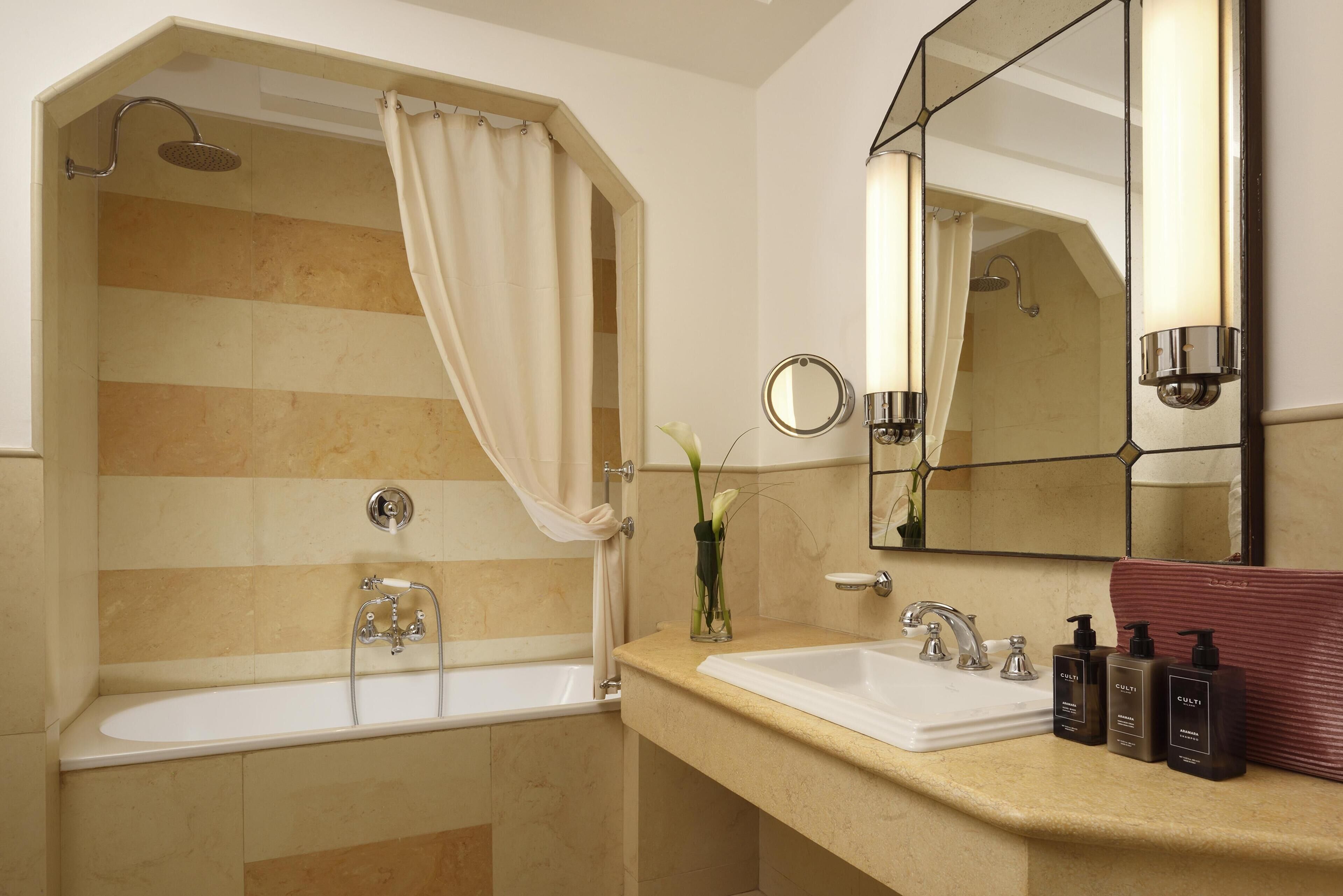 A bathroom with a bathtub, a sink, a mirror, and toiletries.