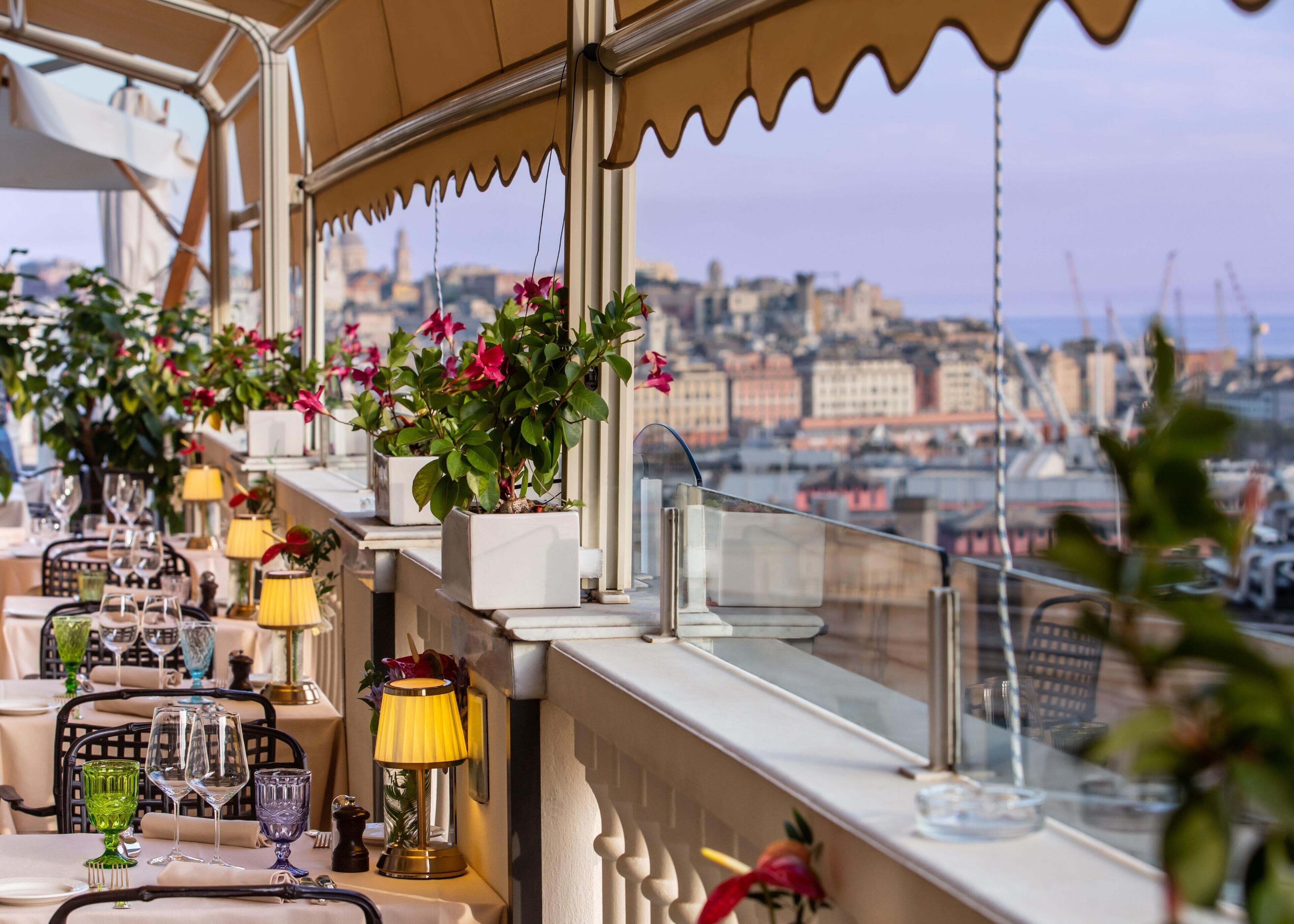 A table set with wine glasses and a lamp, overlooking a cityscape.
