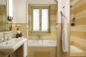 A bathroom with a bathtub, a sink, a mirror, and a window with curtains. - Grand Hotel Savoia Genova, Curio Collection by Hilton (Genoa)