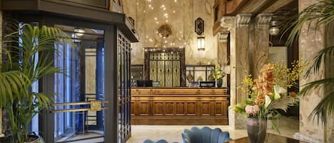 A lobby with a reception desk, seating area, and a large vase of flowers.