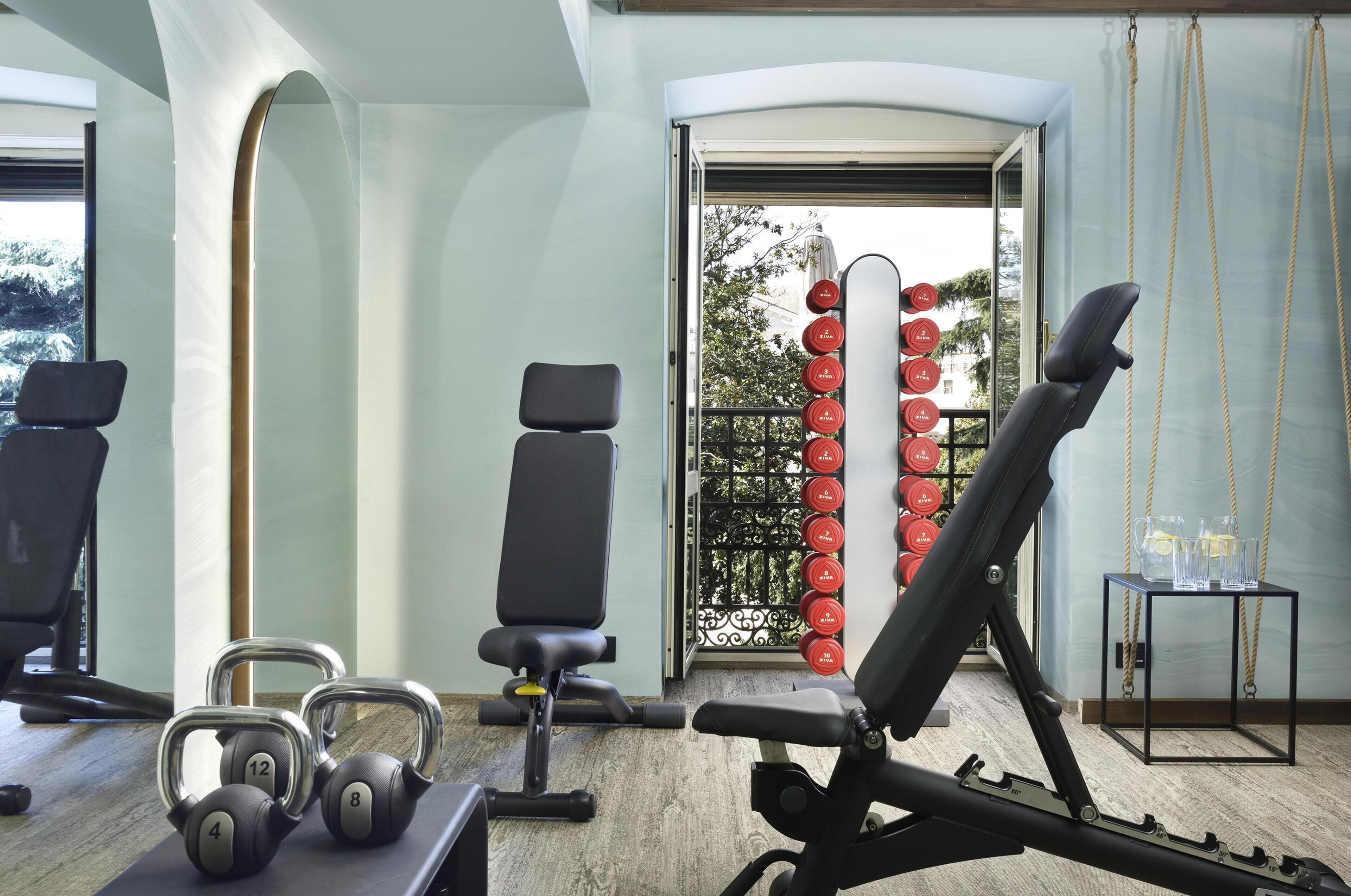 A gym with exercise equipment, a bench, and a wall-mounted dumbbell rack.