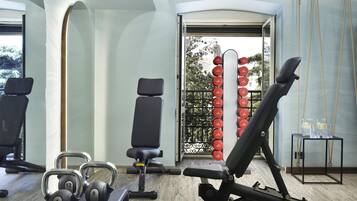 A gym with exercise equipment, a bench, and a wall-mounted dumbbell rack.
