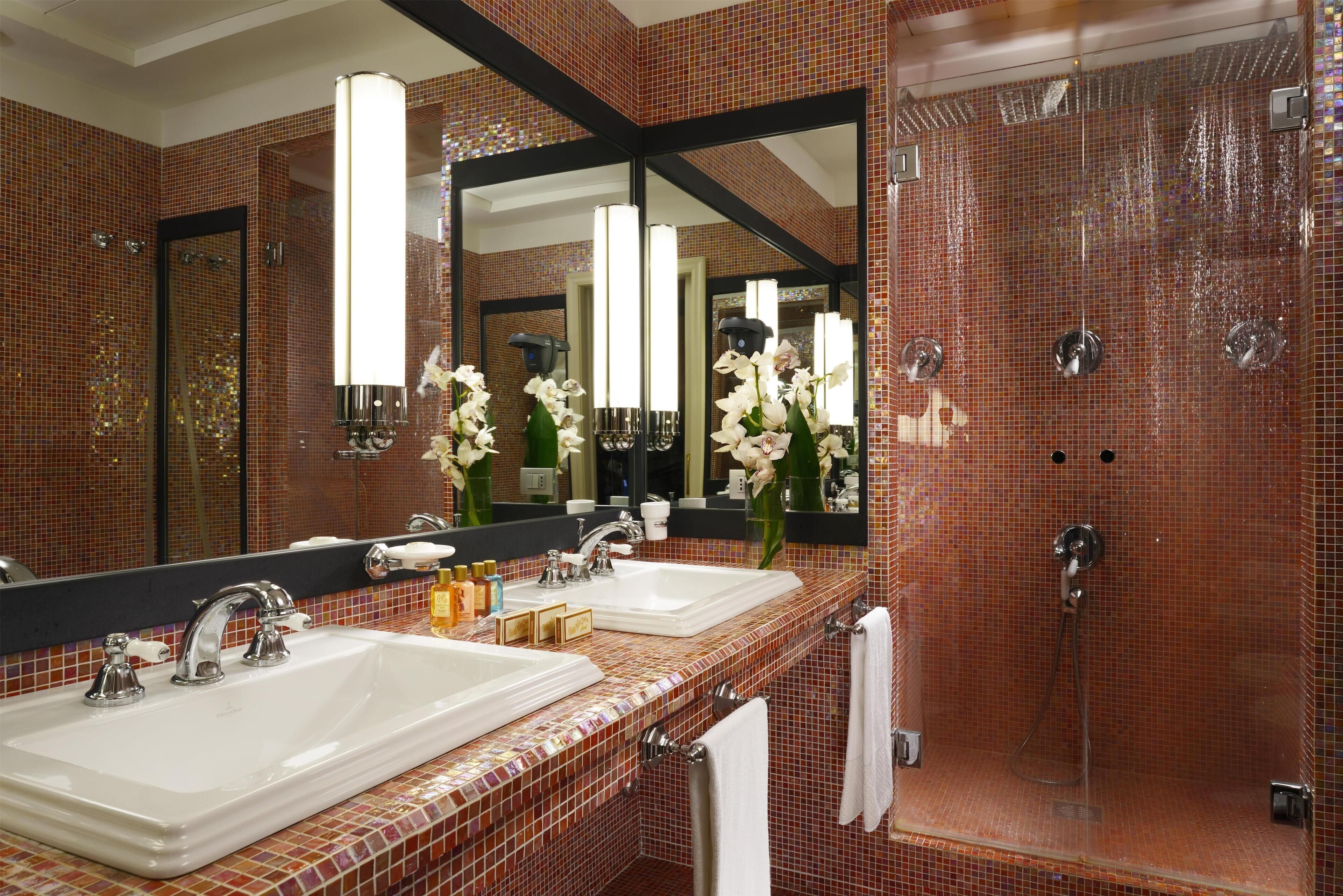 A bathroom with two sinks, a large mirror, and a shower area.