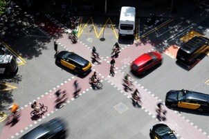 A busy intersection with multiple lanes for vehicles and bicycles, a bus, and pedestrians.