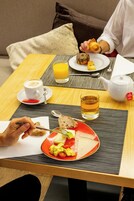 A breakfast setting with a plate of food, a cup of coffee, a glass of orange juice, and a teapot on a table.