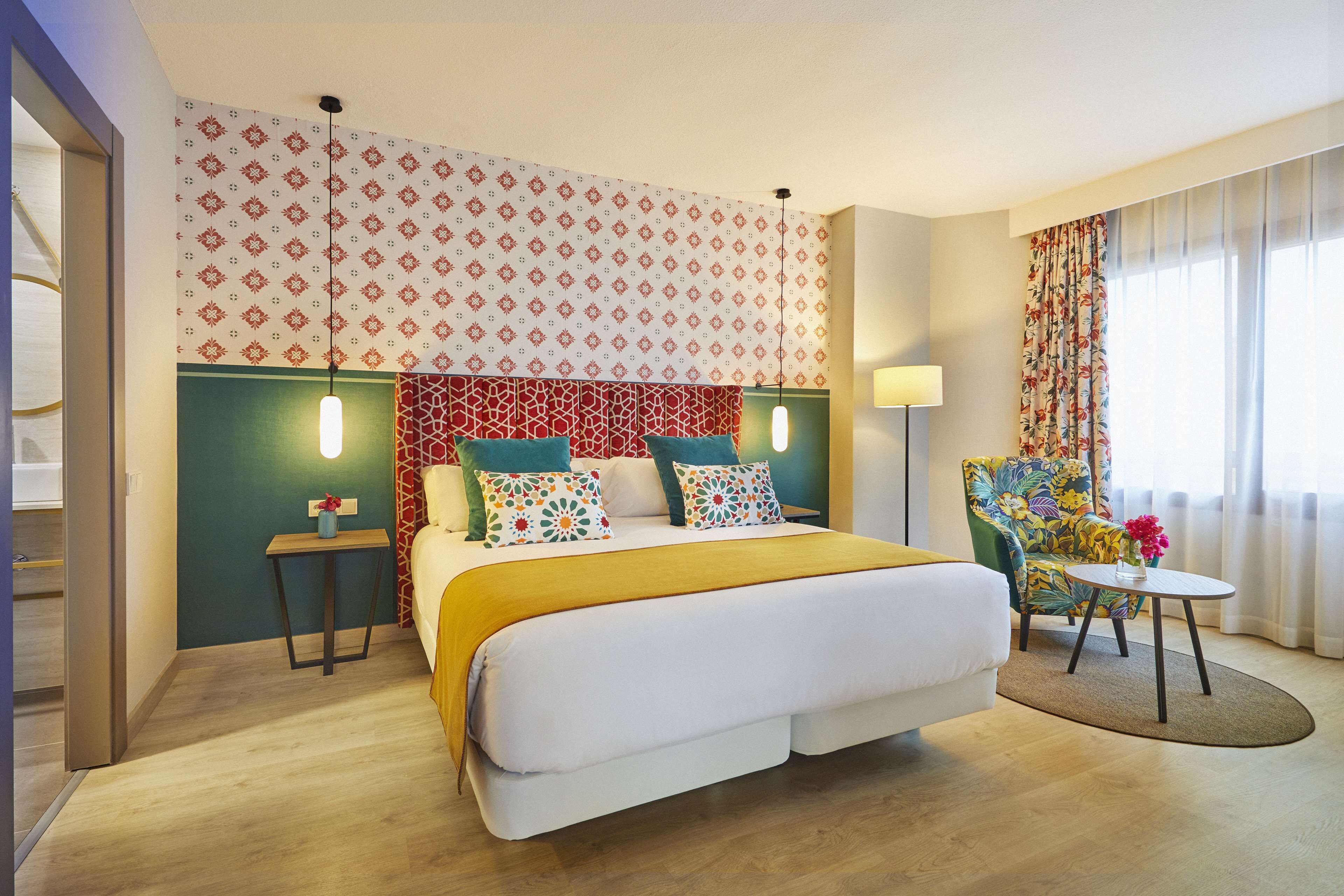 Una camera d'albergo con un letto grande, un tavolino, una sedia e una parete decorata.