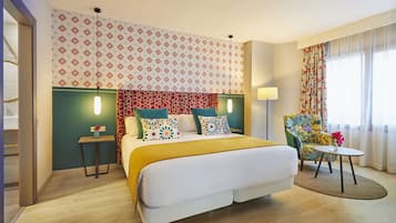 Une chambre d’hôtel avec un grand lit, une petite table, une chaise et un mur décoré d’un motif.