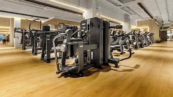 Une salle de sport équipée de nombreuses machines d’exercice disposées en rangées.