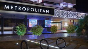 A modern hotel with a prominent "METROPOLITAN" sign, outdoor seating area, and decorative trees. - Hesperia Sevilla (Seville)