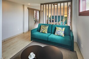 A modern living room with a teal sofa, two patterned cushions, and a coffee table with a cup and saucer.