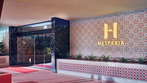 A modern hotel lobby with a glass entrance, patterned wall tiles, and a reception desk. - Hesperia Sevilla (Seville)