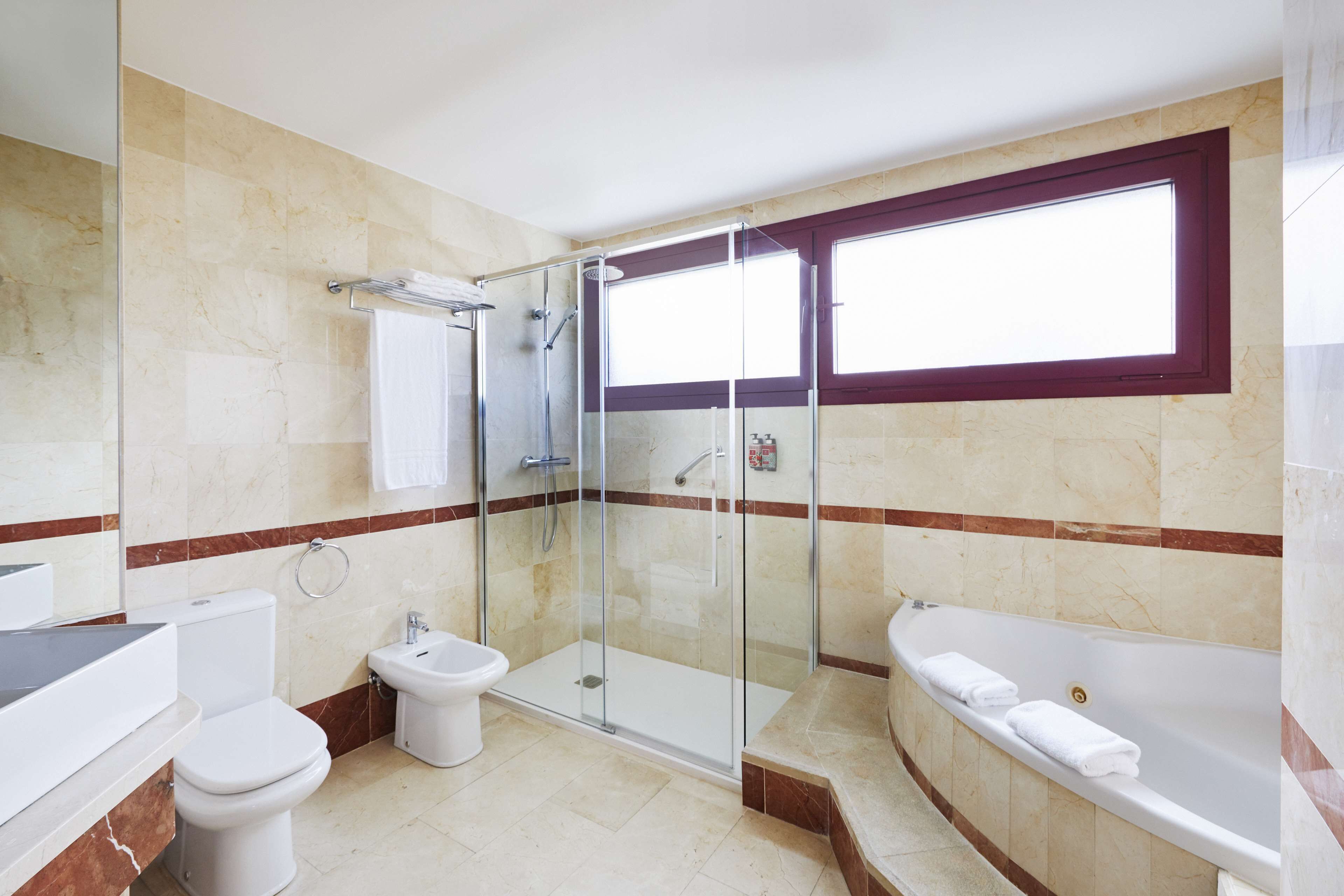 A modern bathroom with a glass-enclosed shower, a bathtub, and a toilet.