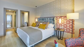 Una habitación de hotel moderna con una cama grande, una mesita pequeña, una silla y un detalle decorativo en la pared.