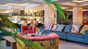 A modern hotel lobby with a bar area, seating arrangements, and decorative elements.