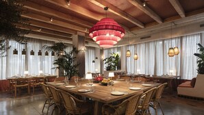 A spacious dining area with a large wooden table, wicker chairs, and pendant lighting. - Hesperia Sevilla (Seville)