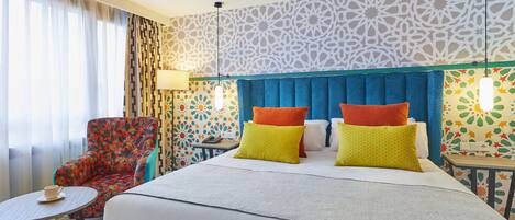 Une chambre d’hôtel avec un grand lit, une chaise, une petite table et un mur décoré d’un motif.