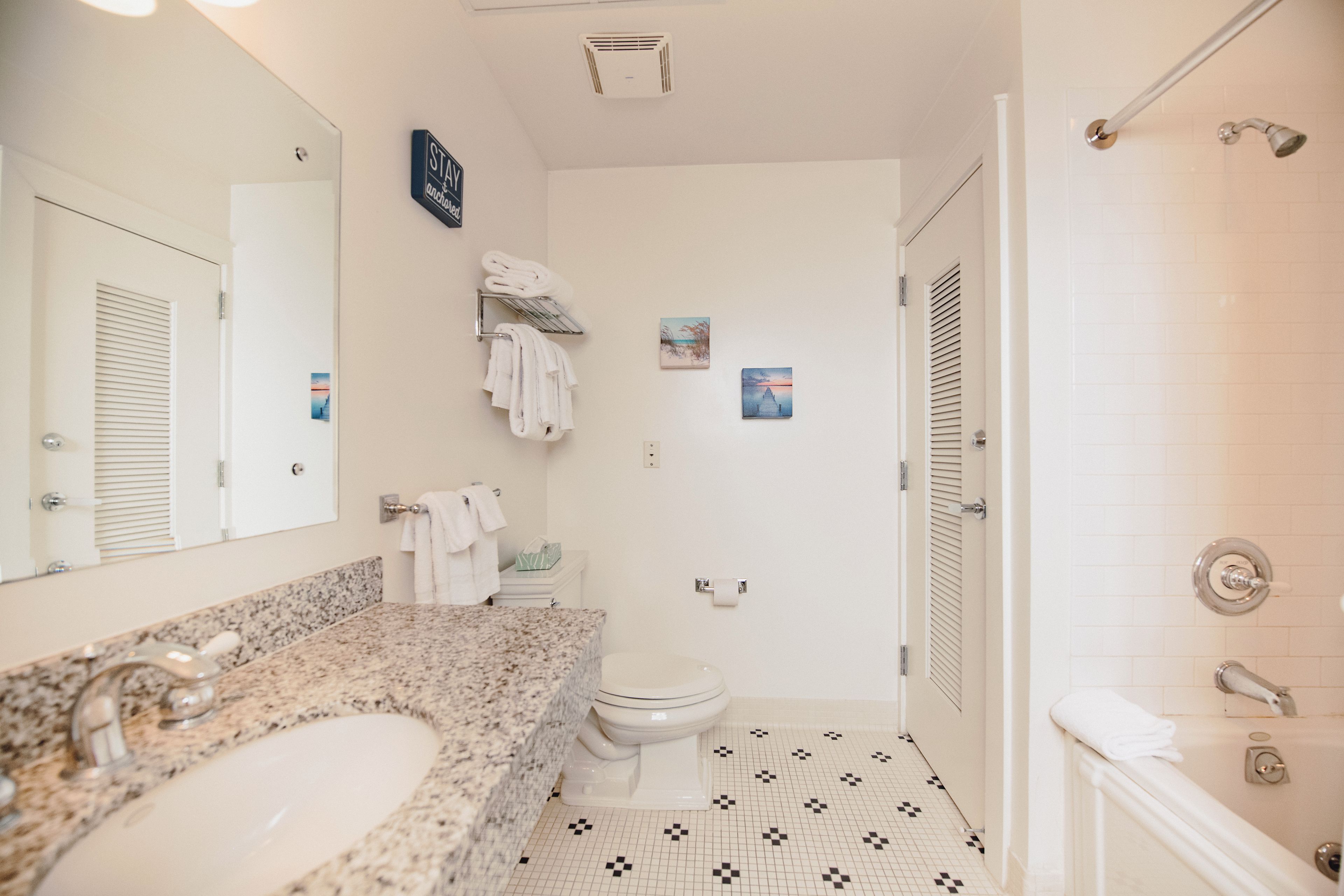 A bathroom with a granite countertop, a white toilet, a towel rack, and a shower area.