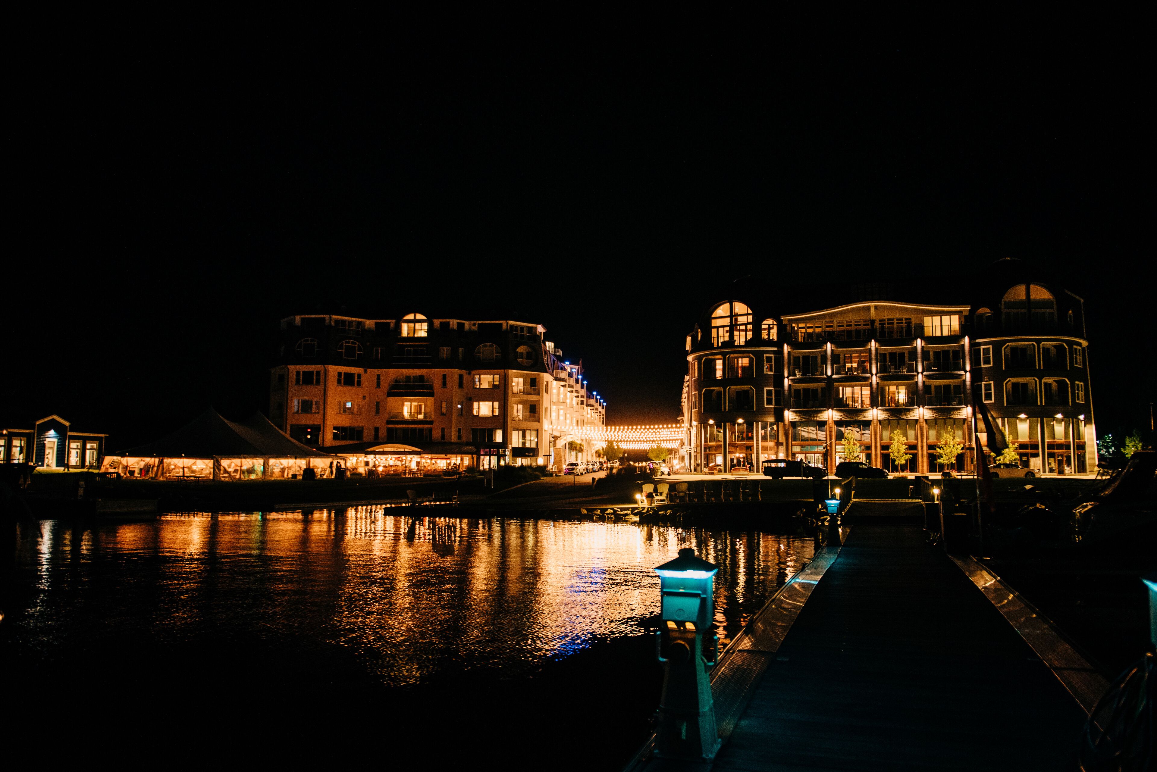A waterfront hotel with multiple buildings, a reflective water body, and a pathway leading to the entrance.