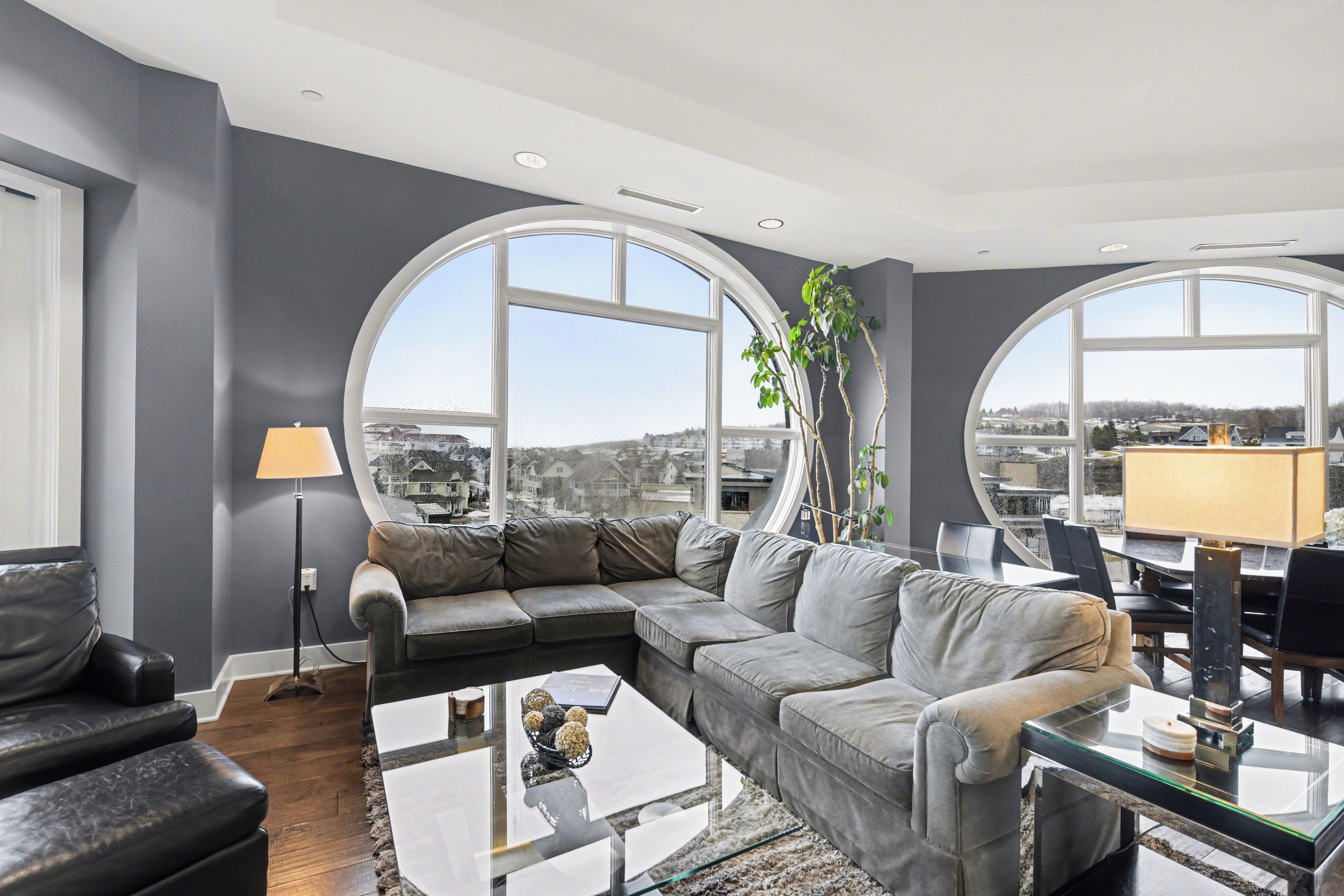 Una sala de estar moderna con un sofá modular, una mesa de centro de vidrio y grandes ventanales que ofrecen vistas a la ciudad.