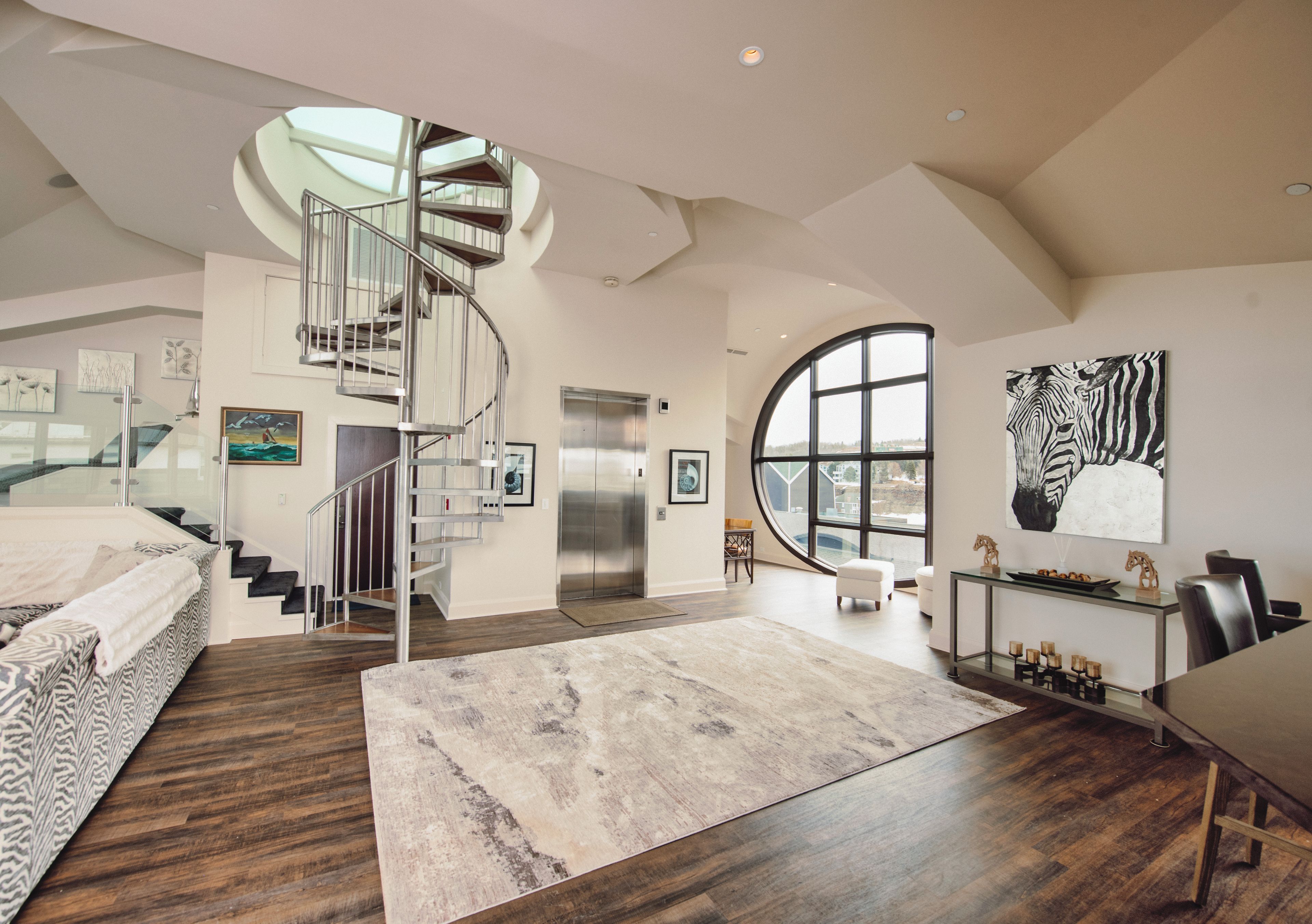 Un intérieur spacieux agrémenté d’un escalier en colimaçon, d’une grande fenêtre et d’un tableau représentant un zèbre.