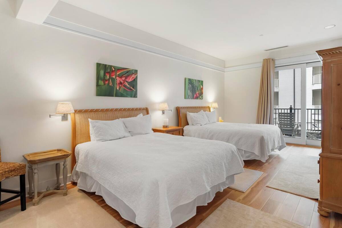 A hotel room with two beds, a balcony, and artwork on the walls.