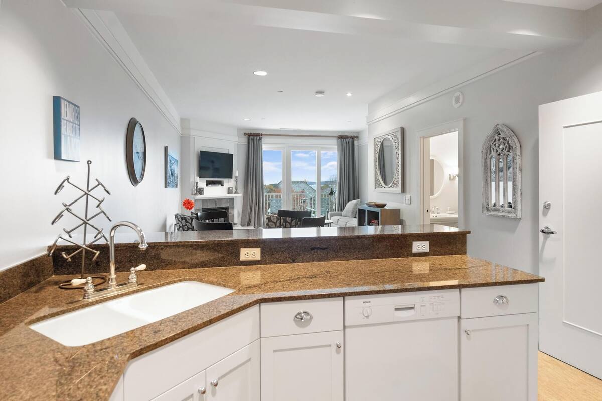 A modern kitchen with granite countertops, a built-in sink, and white cabinetry.