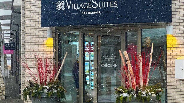 L’entrée d’un hôtel, avec une enseigne indiquant « VillageSuites Bay Harbor » et un panneau « Enregistrement » sur la porte.
