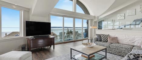 A spacious living room with a large flat-screen TV, a comfortable sofa, and a coffee table.