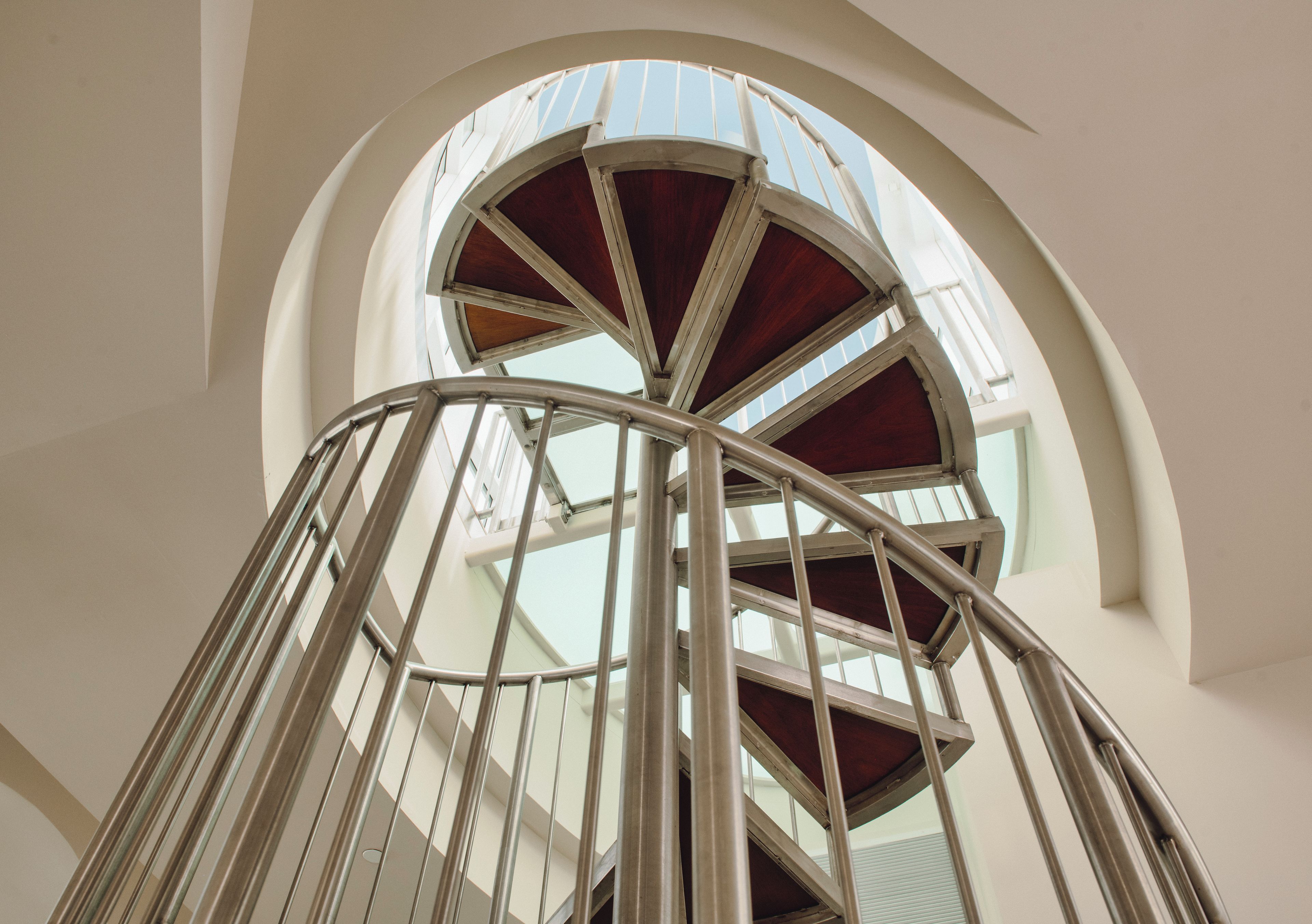 A spiral staircase with metal railings and wooden steps, leading upwards.