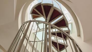A spiral staircase with metal railings and wooden steps, leading upwards.