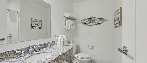 A bathroom with a granite countertop sink, a white toilet, and a wall-mounted towel rack.