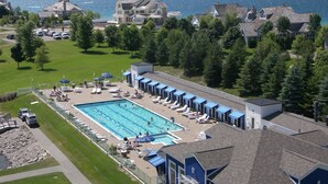 A large swimming pool with multiple lounge areas and a view of the sea. - Village Suites Bay Harbor (Petoskey)