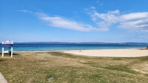 A beach with a sign reading "Sunset Beach," a grassy area, and a clear blue sky.