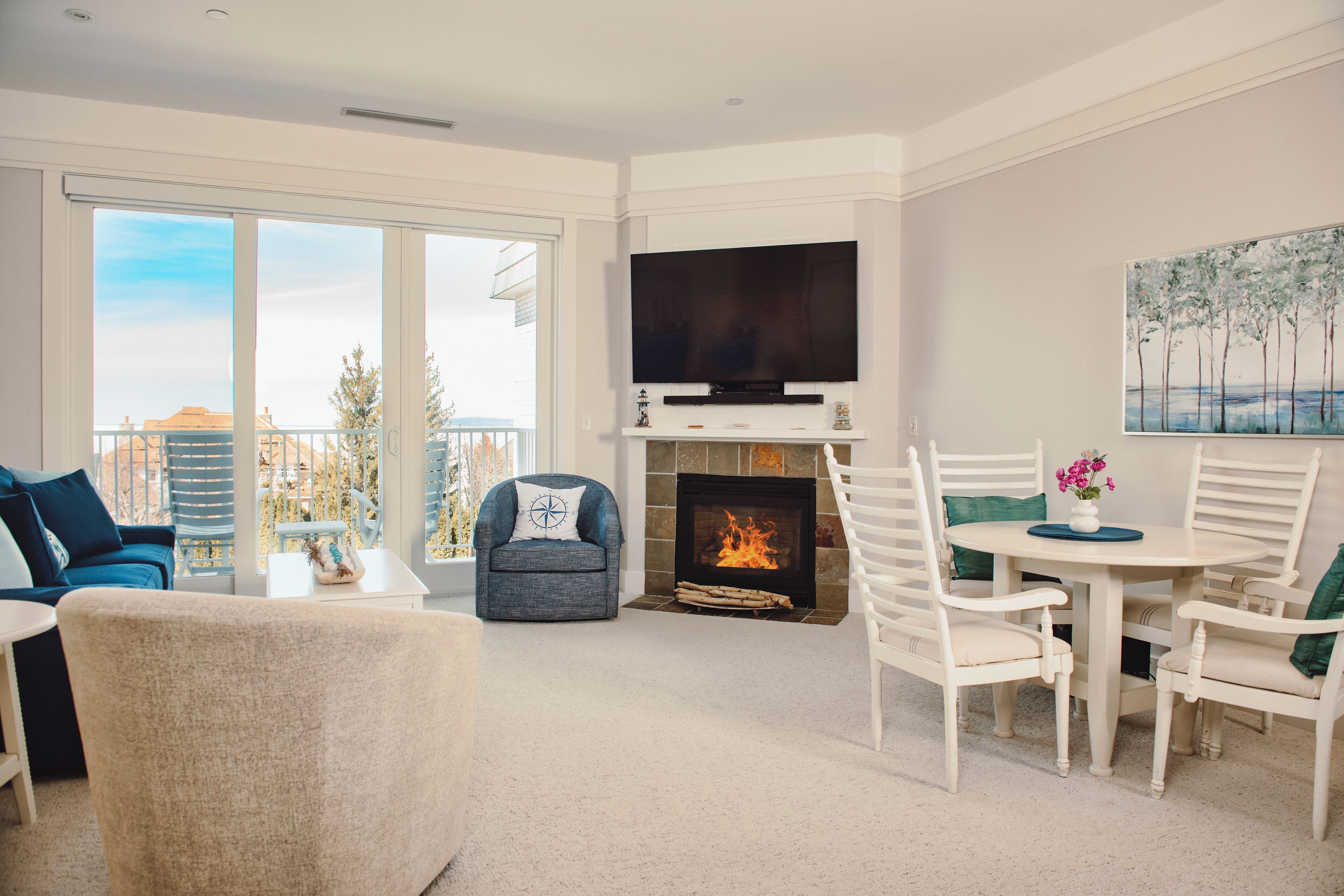 A modern living room with a fireplace, a flat-screen TV, and a dining area.