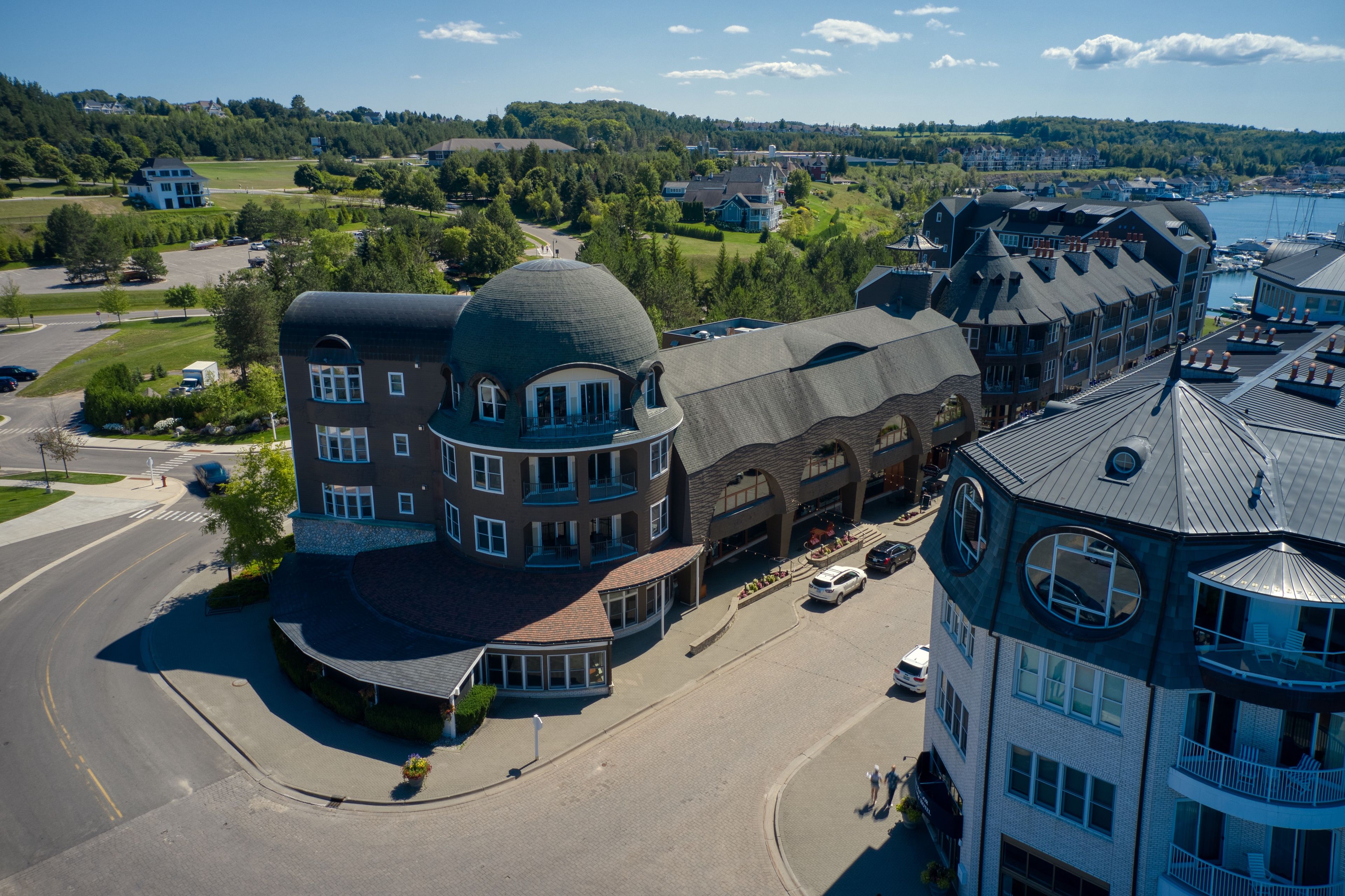 A multi-story building with a distinctive dome and turret, located in a coastal town with a marina visible in the background.