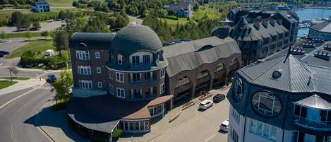 A multi-story building with a distinctive dome and turret, located in a coastal town with a marina visible in the background.