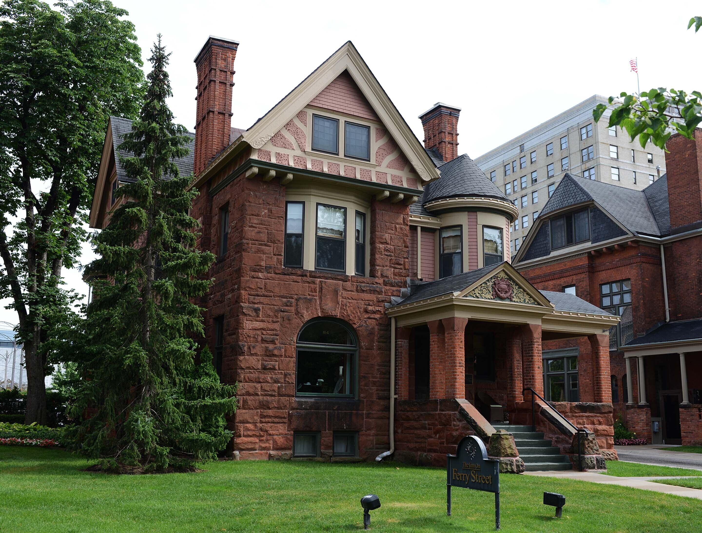 A historic brick building with a prominent entrance, a bay window, and a turret.
