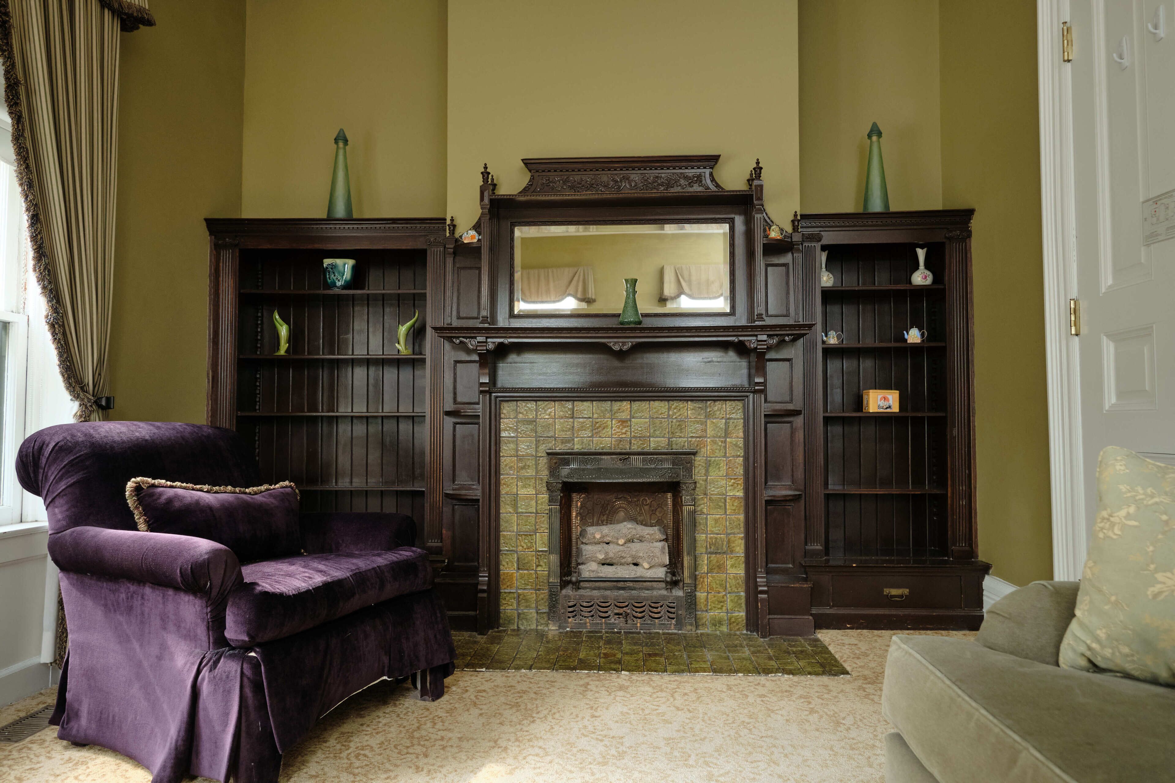 Una sala de estar con chimenea, muebles de madera oscura y una pared verde.