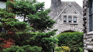 A historic building with a stone facade, a turret, and an arched entrance.