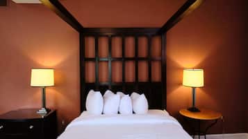 Une chambre d’hôtel avec un grand lit, deux tables de chevet avec des lampes et une tête de lit sombre.