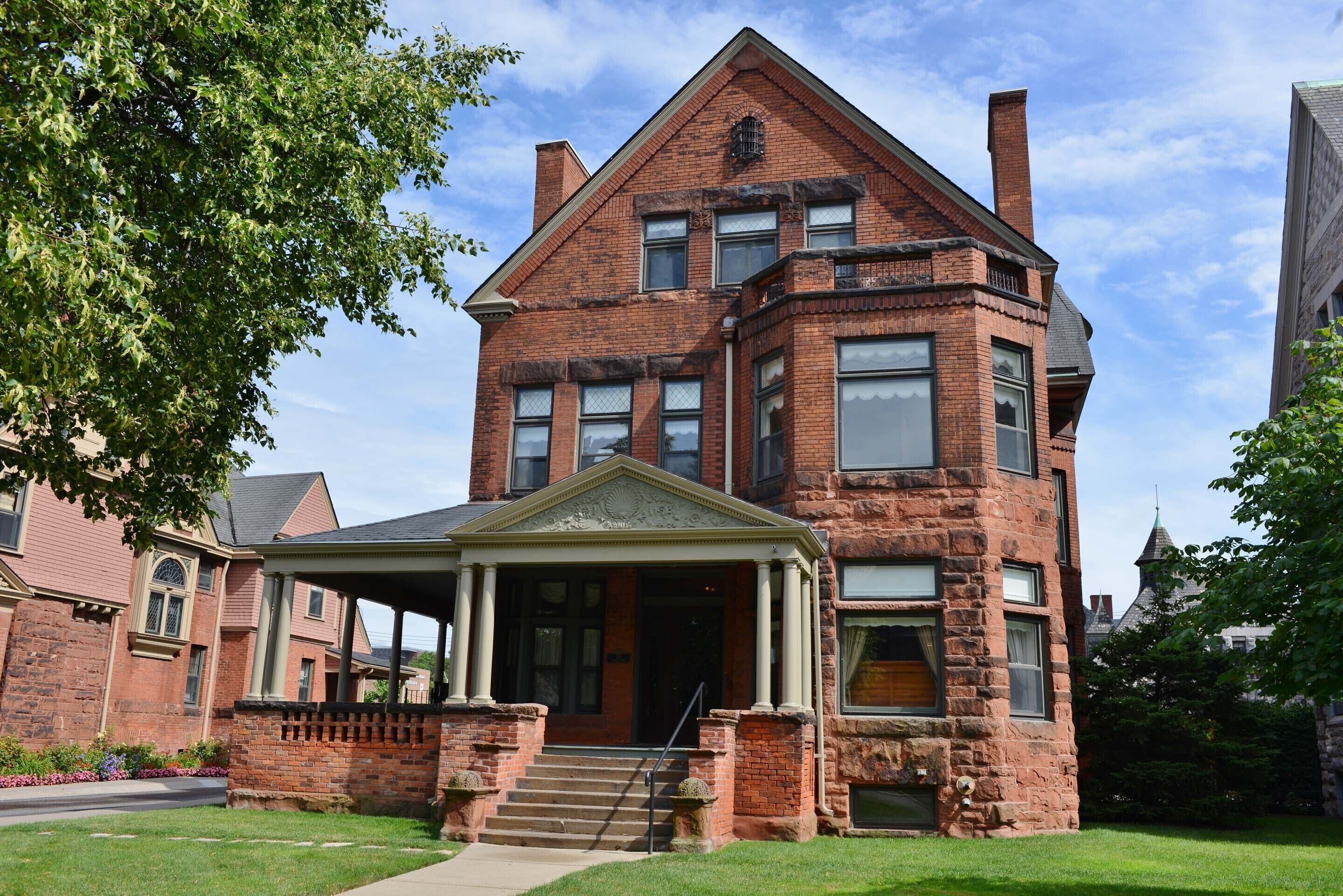 A large brick building with a prominent entrance, a covered porch, and a symmetrical facade.