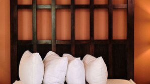 A hotel room with a large bed, a headboard with a grid pattern, and a warm wall color.