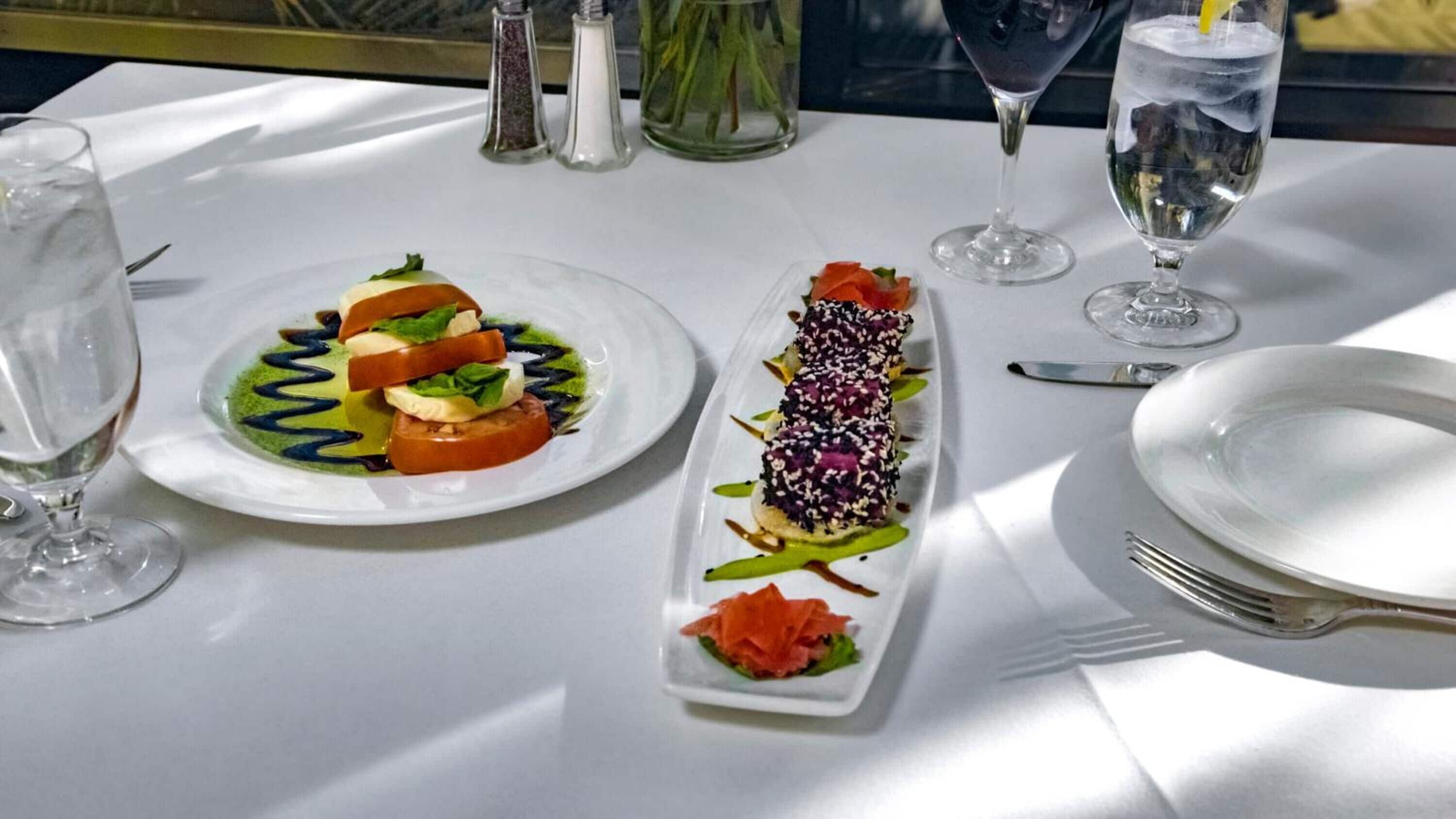 Une table dressée pour le dîner, avec deux assiettes de nourriture, un verre d’eau et une coupe de champagne.
