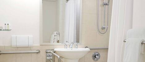 Une salle de bain équipée de toilettes, d’un lavabo, d’une douche et d’un miroir.