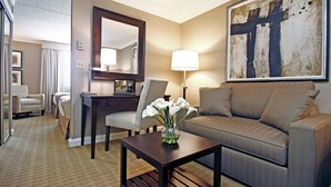 A hotel room with a sofa, armchair, desk, and a large mirror. - Ethan Allen Hotel (Danbury)