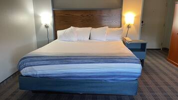 Een hotelkamer met een groot bed, twee bedlampen, een nachtkastje en een houten hoofdeinde.