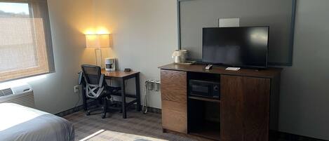 Une chambre d’hôtel avec deux lits, un bureau avec une chaise, une télévision et une lampe.