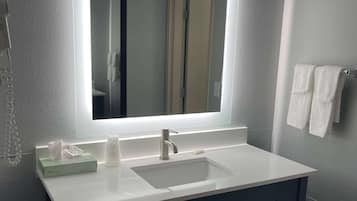 A bathroom with a white sink, a mirror, and a towel rack.